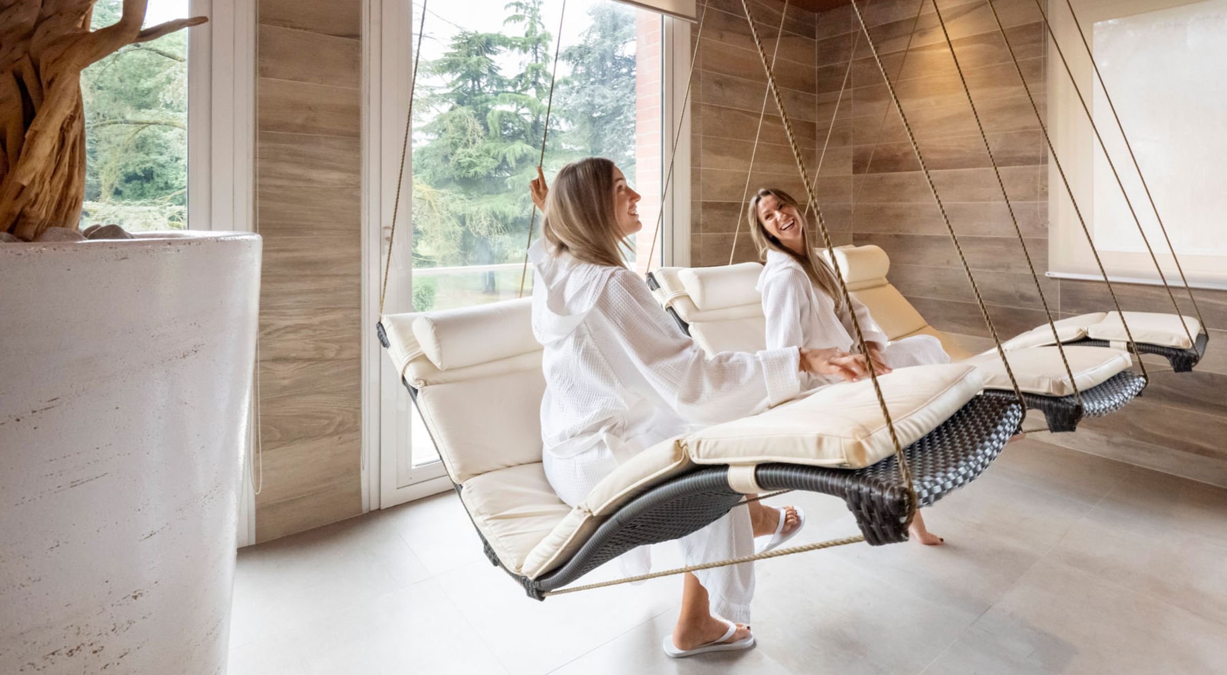 Due ospiti si rilassano sulle chaise longue sospese nella sala relax della Spa nel Parco a Monticelli Terme, Parma